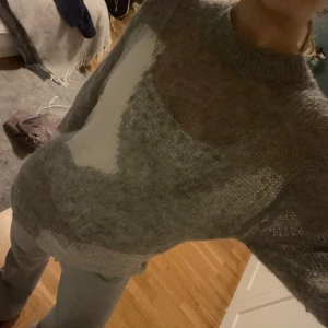 Grå stickad tröja - Säljer en mysig grå stickad tröja med ett unikt mönster i vitt. Tröjan har långa ärmar och en rund halsringning. Den har ett litet hål i ena ärmen, se sista bilden, detta är inget som märks när man har på sig tröjan. Annars är den i fint skick, nypris 400 kr.
