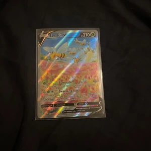 Beedrill V Pokémonkort - Säljer ett holografiskt Beedrill V Pokémonkort med en färgglad design. Kortet har en glansig yta som reflekterar ljus i regnbågens färger. Perfekt för samlare eller Pokémon-entusiaster!