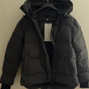 Mörkgrå dunjacka från Canada Goose - Säljer en mörkgrå black label jacka från Canada Goose. Storlek M men passar S helt ny oanvänd tagg finns kvar. Pris kan diskuteras, DM för fler bilder