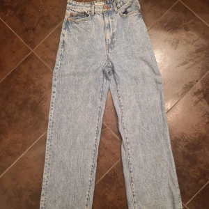 Raka jeans från Lindex modell Hanna. - Säljer ett par ljusa jeans med hög midja och rak passform. Klassisk femficksdesign med knappgylf. De kommer från Lindex och modellen heter "Hanna". De är i stl 34.