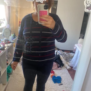 Mörkblå randig tröja från Red - Säljer en mörkblå tröja från Red med röda och vita ränder. Tröjan har långa ärmar och en knytning vid halsen. Perfekt för en avslappnad stil.