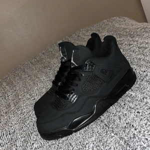 Svarta Nike Air Jordans - Snygga svarta Nike Air Jordans med klassisk design och snörning. Skorna har en stilren look med diskreta detaljer och en ikonisk logga på tungan. Perfekta för dig som vill ha en tidlös sneaker i garderoben.