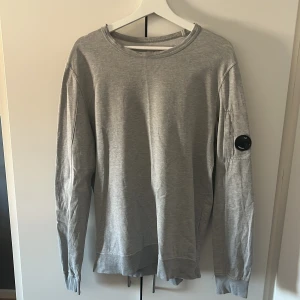 CP Company tröja  - Säljer en stilren grå långarmad tröja av märket CP company. Storlek L. Inga skador eller liknande på tröjan 