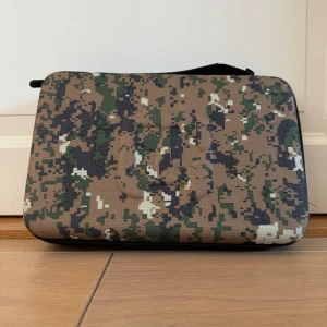 Camouflage förvaringsväska för elektronik från Poluz - Säljer en snygg förvaringsväska från Poluz med ett coolt camouflagemönster. Väskan har en dragkedja och en praktisk innerficka för extra förvaring (se bild 3&4) . Perfekt för att skydda dina tekniska tillbehör med stil! Mått: Längd: 33cm , Bredd: 21,5cm , Höjd: 7cm 