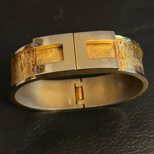 Guldarmband med geometrisk design - Elegant guldarmband rochas&co med en unik geometrisk design. Armbandet har en bred form med en stilren låsning och detaljerad yta som ger en lyxig känsla. Perfekt för att ge en sofistikerad touch till din stil.