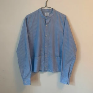 Blå randig skjorta från Zara - Säljer en stilren blå randig skjorta från Zara i storlek M. Skjortan har en avslappnad passform med långa ärmar och knappar framtill. Perfekt för en avslappnad men ändå snygg look.