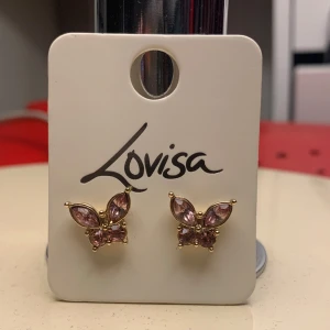 Rosa fjärilsformade örhängen från Lovisa ge järna prisföeslag!😁 - Snygga fjärilsformade örhängen från Lovisa i guld med rosa stenar. Aldrig andvända. Perfekta för att lägga till en touch av elegans och färg till din outfit. De har en fin glittrig effekt som fångar ljuset vackert. Ge gärna prisförslag!😁