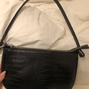 Svart axelväska med krokodilmönster - Snygg svart axelväska i skinnimitation med krokodilmönster, typ aldrig användt💗skriv för fler bilder. Väskan är från other stories💖