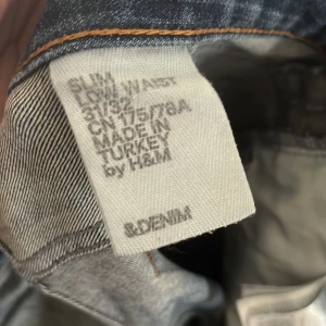 Blå slim jeans storlek 31:32 - Snygga blå slim jeans från H&M med låg midja. De har en klassisk femficksdesign och en lätt tvättad look som ger en avslappnad stil. Perfekta för en casual outfit.