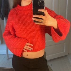 Röd stickad croppad tröja - Säljer en snygg röd stickad tröja med croppad design. Tröjan har långa ärmar och en ribbad struktur som ger en trendig look. Perfekt för att hålla sig varm och stilren under kyligare dagar. Använd fåtal gånger💕