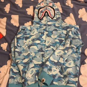 Blå camo hoodie från A Bathing Ape - Säljer en bape hoodie använd några gånger, storleken är s men passar xs också, PRIS KAN DISKUTERAS!