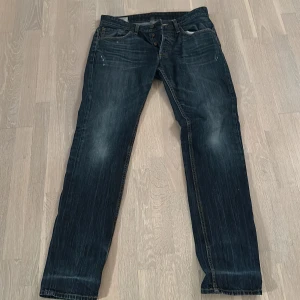 Mörkblå jeansbyxor - Snygga mörkblå jeans med en klassisk straight passform. De har en lätt slitning på knäna och en knappgylf. Perfekta för en avslappnad stil.