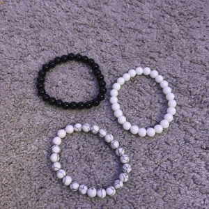 Tre Stockholm stil armband  - Säljer tre elastiska armband med pärlor i olika färger: ett svart, ett vitt och ett med vit och grå marmorering. Perfekta för att mixa och matcha beroende på stil och humör.
