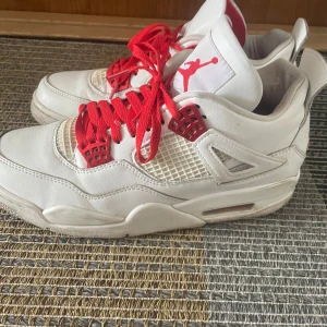 Vita och röda Nike Air Jordans - Säljer ett par vita Nike Air Jordans med röda detaljer och snörning. Skorna har den ikoniska Jumpman-loggan på hälen och tungan. Perfekta för dig som älskar klassiska sneakers med en färgklick. Box finns med och kvitto be om bild så löser jag. (ANVÄND INSTABOX)