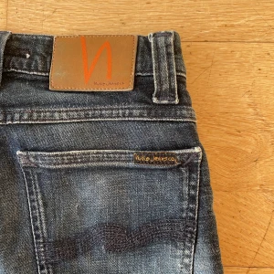 Mörkblå Nudie Jeans - Snygga mörkblå jeans från Nudie Jeans med klassisk femficksdesign. Jeansen har en straight passform och är tillverkade i slitstarkt denim. Perfekta för en avslappnad stil. Sitter riktigt snyggt och är i väldigt bra skick! Skriv om du har några funderingar! 💫👏