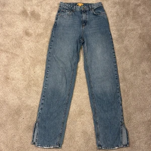 Blå jeans från Gina Young - Snygga blå jeans från Gina Young med en rak passform och slitsdetaljer vid bensluten. Jeansen är midwaist och går att justera i midjan. Säljer pågrund av att de är för små och är använda fåtal gånger. 