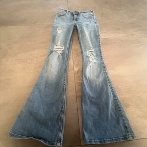 Lågmidjade bootcut jeans hollister - Lågmidjade bootcut jeans från hollister med slitningar!! Så sjukt snygga!!Midjemått: ca 32cm rakt över, innerbenslängd: ca 71cm🌸🌸🌸