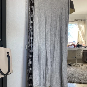 Grå långklänning - Säljer en stilren grå långkjol i mjukt material. Perfekt för en avslappnad look. Kjolen är ganska lång så perfekt om man är lång då den är ganska lång på mig som är 160 ish.