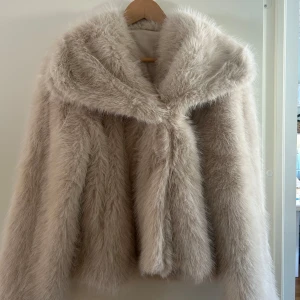 Beige pälsjacka - Säljer en fluffig och stilren beige pälsjacka med långa ärmar. Helt oanvänd.