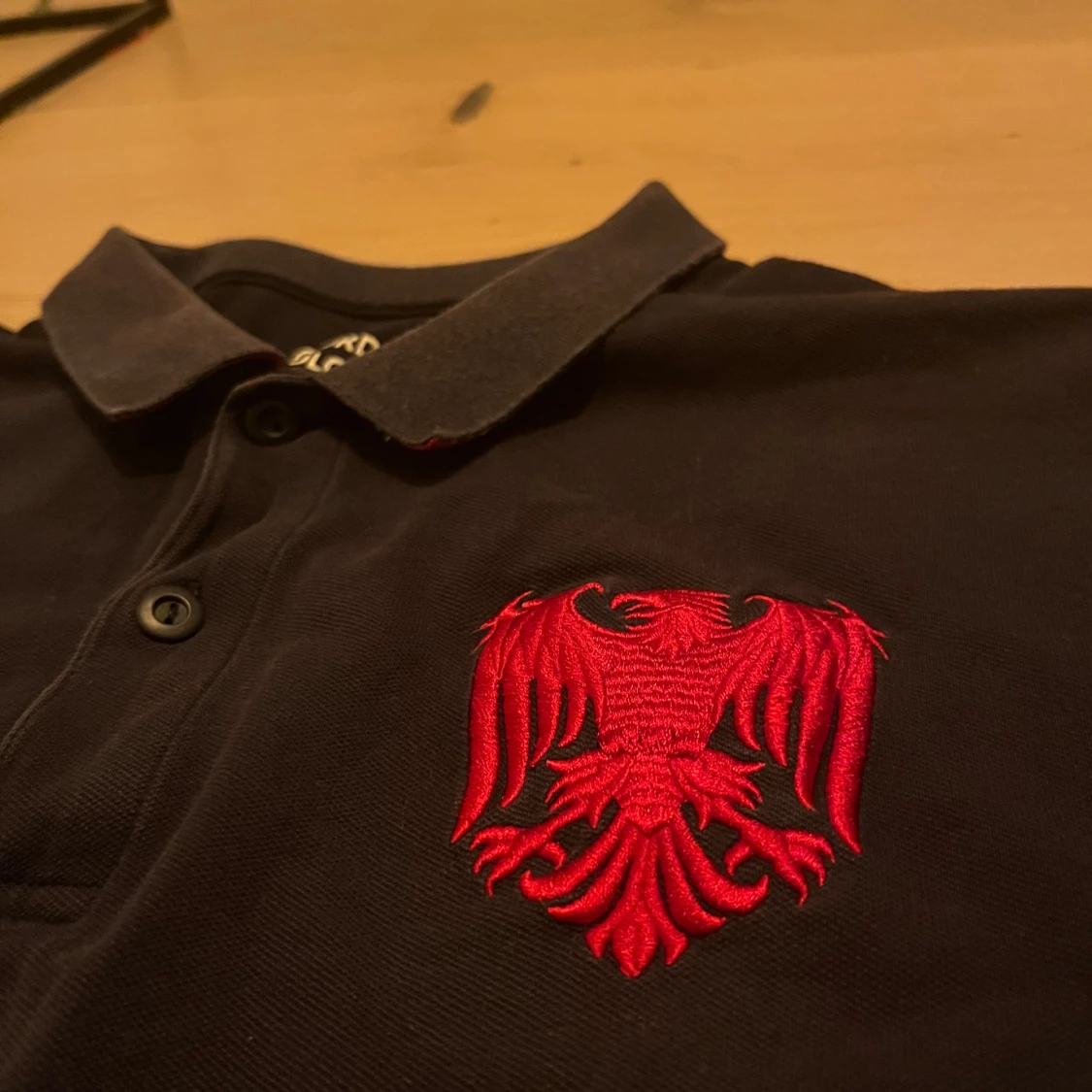 Svart pikétröja med röd broderad detalj - 1