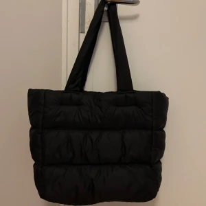 Dun handväska Gina tricot - Skön mjuk dun handväska från Gina tricot, säljs den för jag använder knappt den nu längre. Den är fint skick. Inga repor. Färg svart. Nytt pris 599 kr. Säljs den för 300 kr plus frakt 