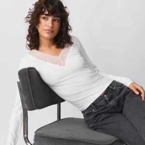 Vit långärmad topp från Gina Tricot - Säljer en superfin vit långärmad topp från Gina Tricot. Den har en vacker spetsdetalj vid den v-ringade halsen som ger en romantisk touch. Perfekt för både vardag och fest! Den är helt oanvänd och lappen sitter kvar. Storlek M.