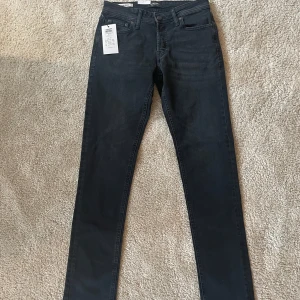 Svarta jeans från Jack & Jones - Säljer ett par snygga svarta jeans från Jack & Jones. De är i nyskick och har en slim passform som sitter riktigt bra (slim Glenn). Storlek 29/32 