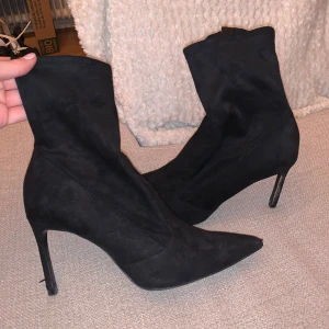 Svarta mocka boots från Zara - Säljer ett par snygga svarta boots i mocka från Zara. De har en spetsig tå och en hög klack som ger en elegant look. Skorna har en dragkedja på insidan. Perfekta för höst och vinter! Lite slitna på klacken, annars fint skick 