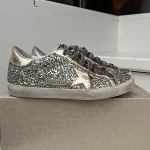 Golden goose - Så fina golden goose skor i jätte bra skick!! Självklart äkta jag har kvar passet (som syns på bild 5) som är äktahetsbevis😊 de är guld silvriga!! Nypris 6400 mitt pris 3099