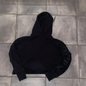 Croppad hoodie - En croppad hoodie, jag klippte av den själv så kanten rullar upp sig. Står Aware på ena armen med stora bokstäver men är väldigt subtilt då texten är i svart. 