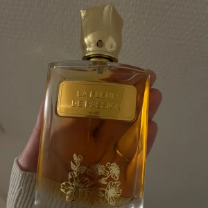 La Fleur De Passion Parfym - Säljer en elegant parfymflaska med namnet 'La Fleur De Passion'. Flaskan är vacker& har guldfärgad kork. Perfekt för den som älskar lyxiga, kanel & äpple dofter av 