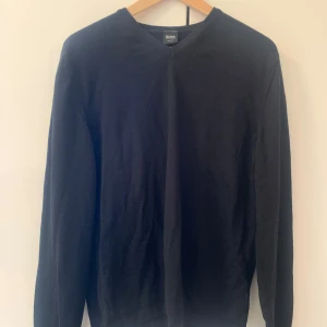Hugo Boss 100% ull - En snygg svart v-ringad stickad tröja 100% ull från Hugo Boss. Står stl L men jag tycker att den är mer en S-M.  Kan gå ner i pris vid snabb affär, hör av er om det är något ni undrar över. 
