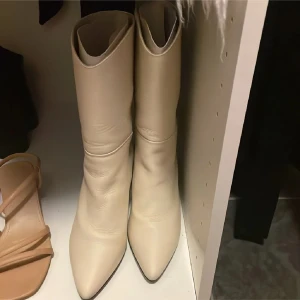 Beige stövletter med spetsig tå - Säljer ett par snygga beige stövletter i skinn med spetsig tå. De har en stilren design och passar perfekt för både höst och vår. De är i nyskick, från samsoe samsoe 