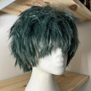Mörkgrön Peruk, Arda Wigs Hansel CLASSIC. Deku cosplay - Stylad och klippt efter karaktären Deku från My Hero Academia. Kort mörkgrön peruk från Arda Wigs och peruken heter Hansel CLASSIC i färg Olive. Heat-resistant. Peruken är tjock och går att jobba med och forma.  Använd flertal gånger. 