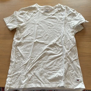 Tommy Hilfiger T-shirt - storlek M  - Vit T-shirt från Tommy Hilfiger med V-formad krage. Normal passform.
