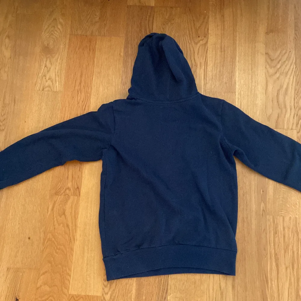 Säljer en snygg mörkblå hoodie från Levi's med deras ikoniska logga i rött och vitt på bröstet. Den är i bra skick och perfekt för både höst och vinter. Hoodien har en klassisk passform med en stor ficka fram och långa ärmar. Perfekt för en casual look!. Tröjor & Koftor.