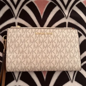 Beige plånbok från Michael Kors - Intressekoll på min snygga plånbok från Michael Kors (självklart äkta).💕Plånboken har flera fack för kort och ID. Perfekt för både vardag och fest. Använt ett par  gånger men finns inga defekter och känns hely ny! Säljer för 900 kr , Orginalpris: 1700