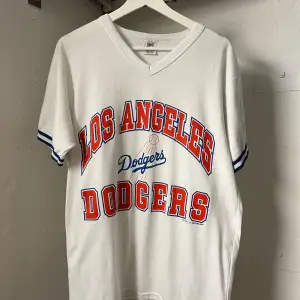 Vintage los angels dodgers T-shirt från 1987 märke logo 7 Made in USA  Litet hål i armhålan se bild 5 lätt att laga :). Saknar storlek men uppskattas vara mellan M och L se mått: Längd 69cm bred 50cm Pris kan diskuteras!