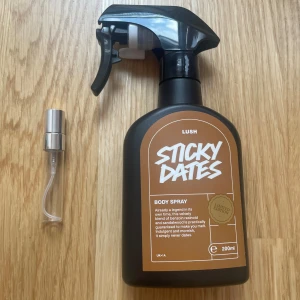 Sticky Dates Body Spray från Lush - Säljer en 5 ml av Lush Sticky Dates Body Spray. Den har en cool svart sprayflaska med en brun etikett. Doften är en härlig blandning av dadlar och sandelträ, perfekt för att känna sig fräsch och unik. Perfekt för daglig användning eller speciella tillfällen!