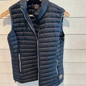 Svart dunväst från Colmar - Säljer en snygg och praktisk marinblå dunväst från Colmar. Västen har en dragkedja framtill och två fickor med dragkedjor. Perfekt för lager-på-lager under höst och vår. Den är i nyskick!!