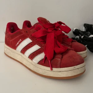 Röda Adidas Campus sneakers - Snygga röda Adidas Campus sneakers med vita ränder och matchande röda snören. Skorna är välanvända men inte dåliga på något sätt. Säljer endast för att dom inte passar mig 🤗 Pris går att diskuteras kom gärna med bud