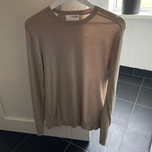 Beige tröja  - Säljer en stilren beige tröja från selected homme.  Tröjan är långärmad och har en klassisk rund halsringning. Perfekt för en avslappnad och elegant look. Tröjan är inte så tjock så väldigt skön att ha på sig om man ska vara inomhus men även väldigt lätt att bara dra på sig en jacka så blir de varmt om man ska vara ute. 