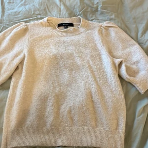 Beige tröja från Vero Moda - Säljer en stilren beige tröja från Vero Moda. Tröjan har en rund halsringning och korta ärmar med en lätt puffig design. Perfekt för en avslappnad och chic look.