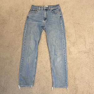 Blå jeans från ONLY - Säljer ett par klassiska blå jeans från ONLY. De har en straight passform och är tillverkade i denim. Perfekta för en avslappnad stil. Midjan är midwaist och de har en traditionell femficksdesign. Finns två små flöckar på ena benet som knappt syns.
