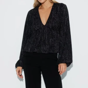 Svart glittrig blus - Snygg svart glittrig blus med v-ringning och långa ärmar. Perfekt för en kväll ute eller festliga tillfällen. Endast använd 2 gånger💗