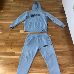 Ljusblå 2delar hoodie och byxor från Hoodrich - Säljer ett set med ljusblå  hoodie och matchande byxor från Hoodrich. Verkliga färgen är som bild 1-2 Hoodien har en stor ficka framtill och byxorna har elastisk midja. Båda plaggen har broderad logga i mörkblå och grå.
