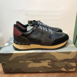 Valentino Rock Runners. Nytt skick - Snygga Valentino Rockrunners i svart och mörkblått med röda detaljer. Kvitto finns. Allt som finns i bilden ingår