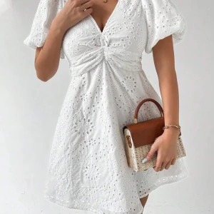 Vit klänning med puffärmar - Säljer en söt vit klänning med puffiga kortärmar och v-ringning. Klänningen har ett fint broderat mönster och en knytning framtill som ger en fin detalj. Perfekt för sommarens alla tillfällen och student!