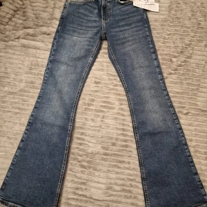 Blå bootcut jeans från Perfect Jeans - Snygga blå bootcut jeans från Perfect Jeans i modellen 'low waist tall bootcut'. De är köpta från gina tricot och har en klassisk femficksdesign och en låg midja.  De är helt nya och har prislappen på. De var för små men tappade bort kvittot så kunde inte lämna tillbaka.