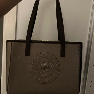 Us polo assn väska - Snygg brun väska från us polo assn, säljer då den ej kmr till användning längre💗har knappast använts och den är perfekt för vardagen